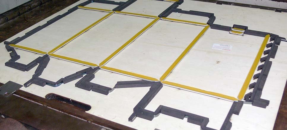 A finished steel-rule die board laid flat, the cutting lines set out for a carton