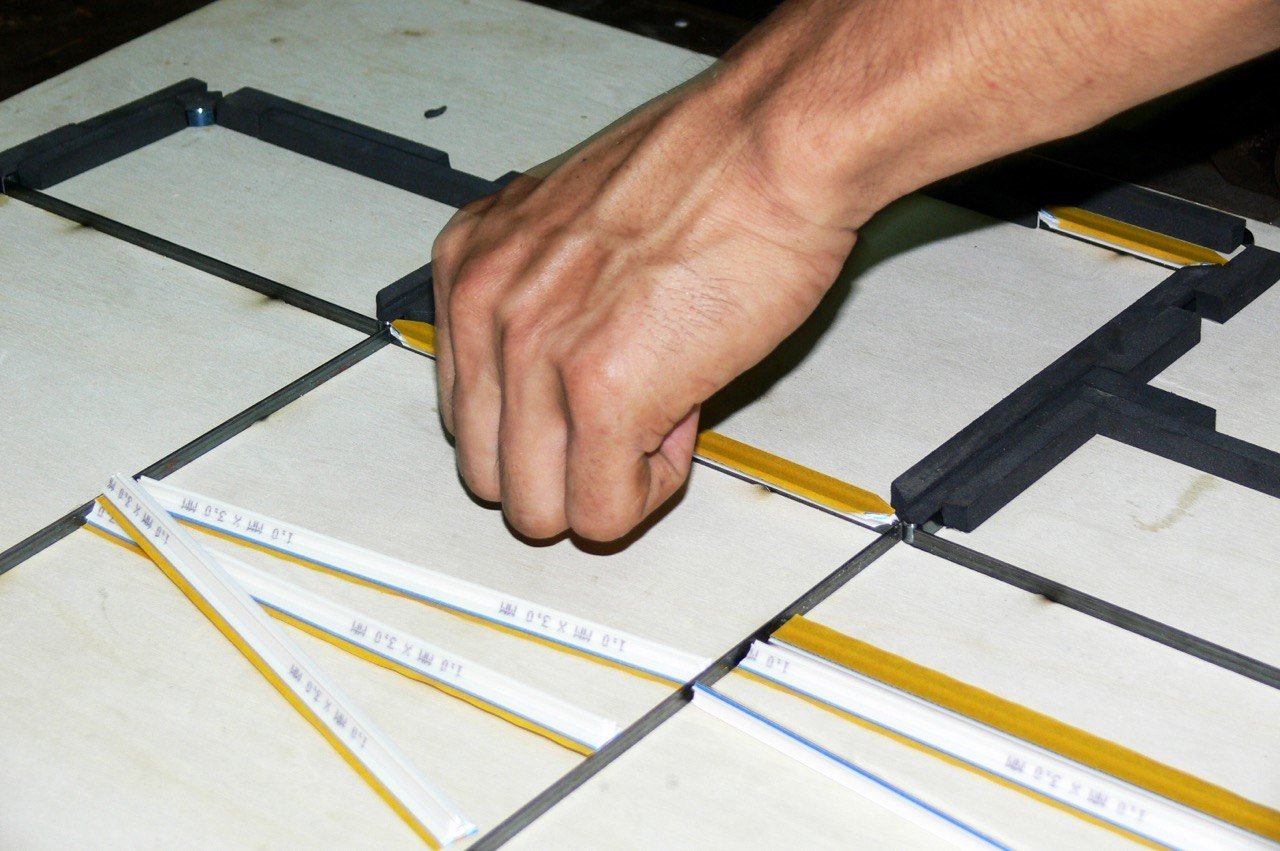 A hand setting steel cutting rule into a die board in the FirstPack die shop