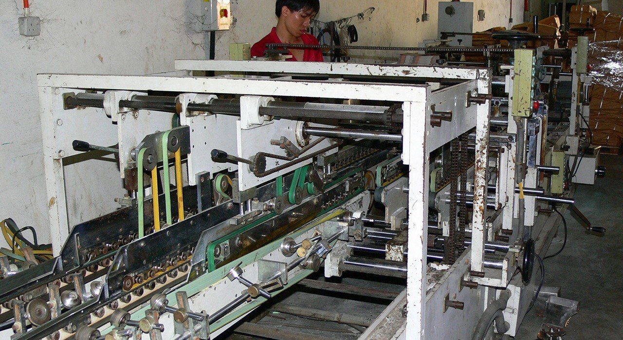 The folder-gluer conveyor line running the length of the floor