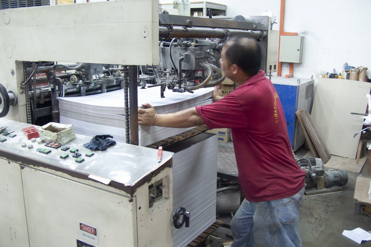 A FirstPack operator guiding a stack of paper on the cutter