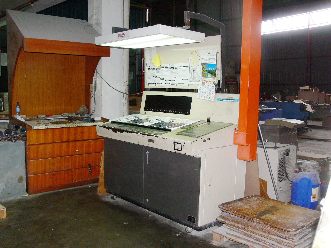 The colour-inspection desk: a viewing lamp over the press console, printed sheets laid out for checking