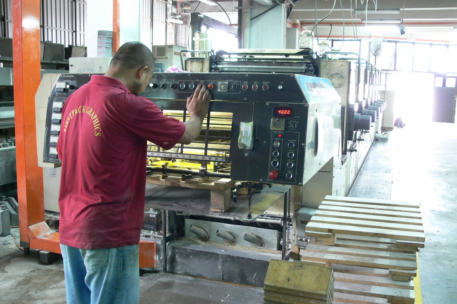A FirstPack operator in the company polo at the press console, the speed display reading 4,000 sheets an hour